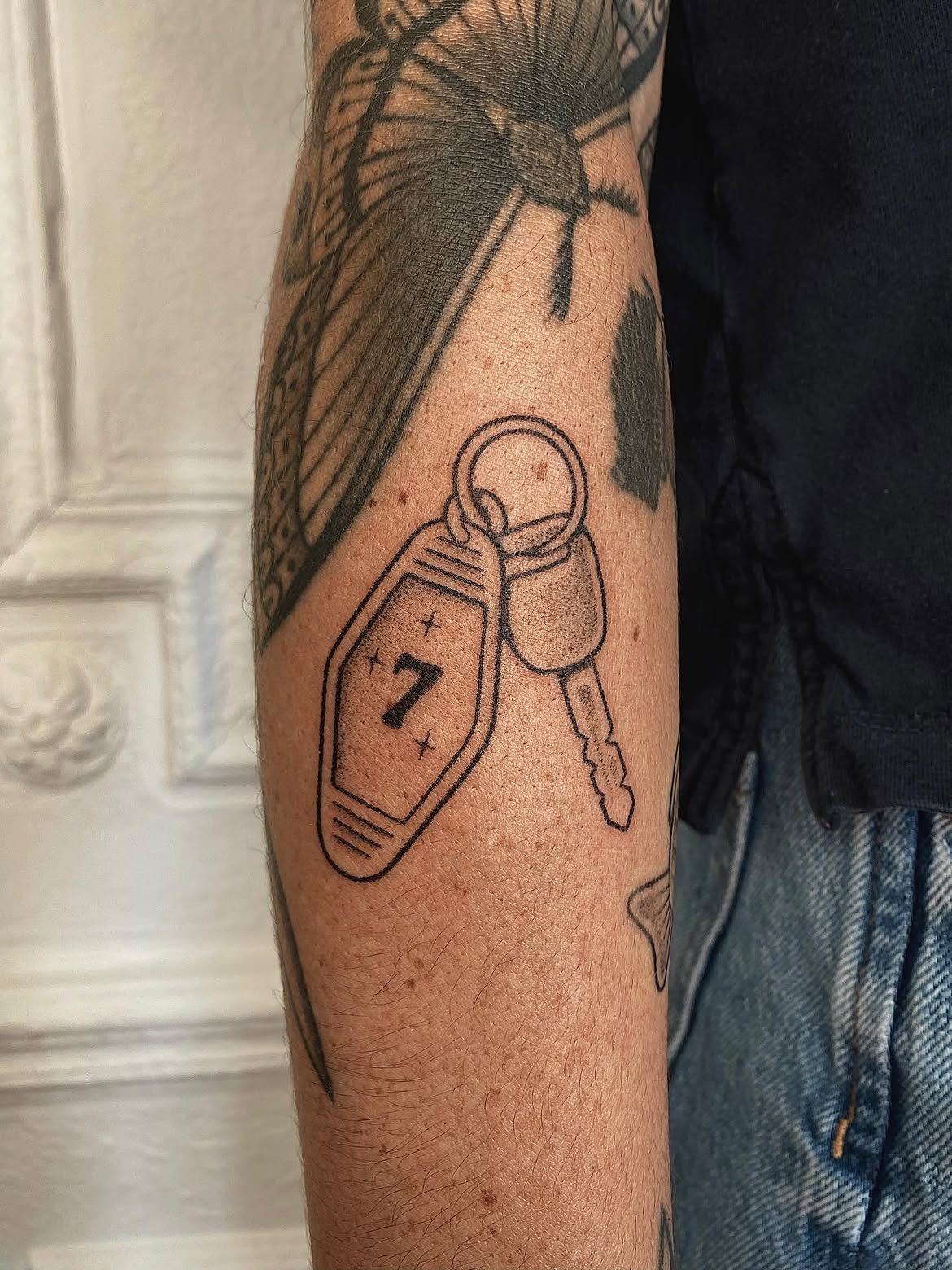 Tatouage handpoke d'une clé avec porte-clé numéro 7 sur l'avant-bras