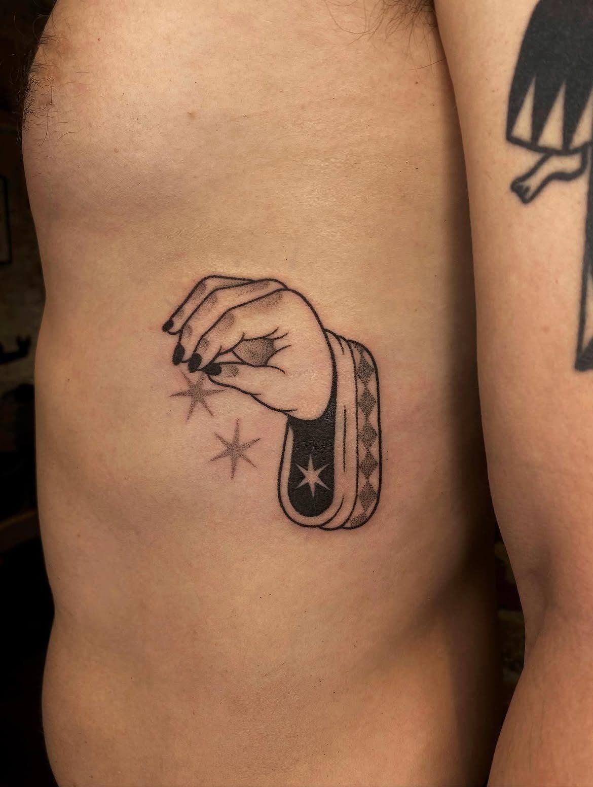 Tatouage handpoke d'une main tenant des étoiles